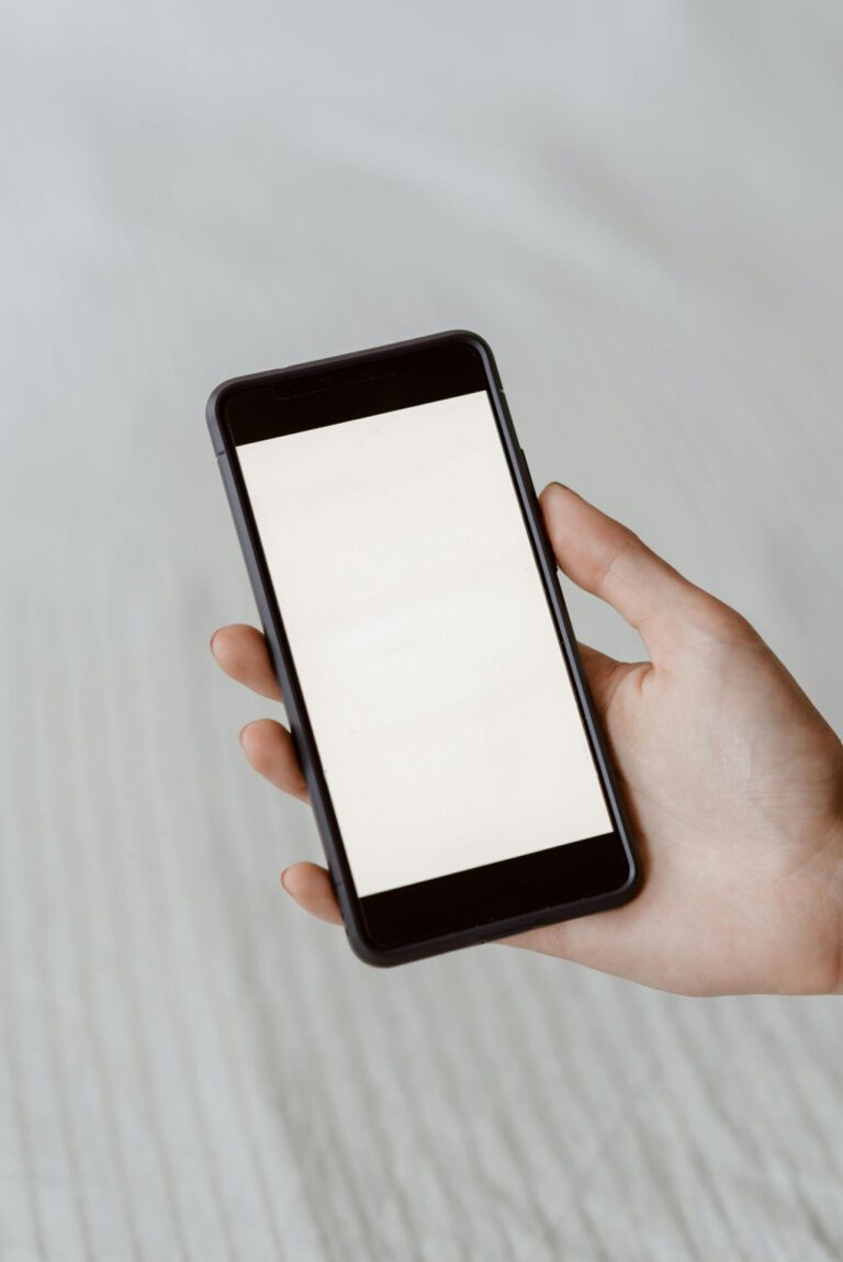 A close-up of a hand holding a smartphone with a blank screen, perfect for mockups.